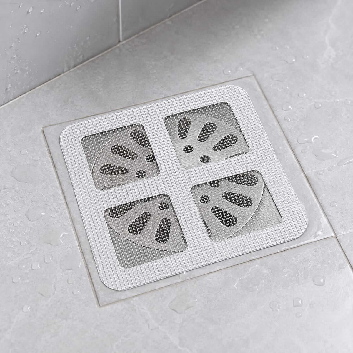 Disposable drain hair catcher mesh sticker placed over a bathroom floor drain
